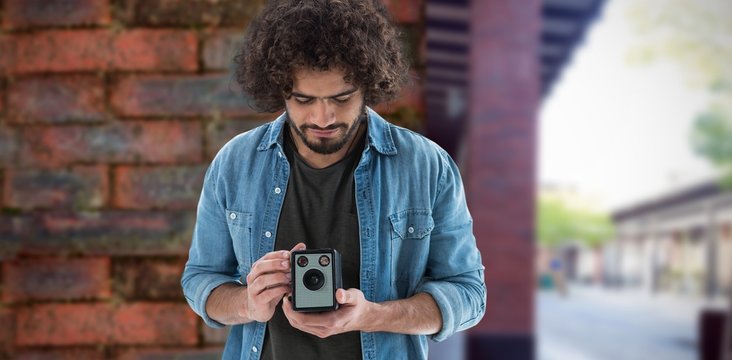 Composite image of male photographer looking at vintage camera 