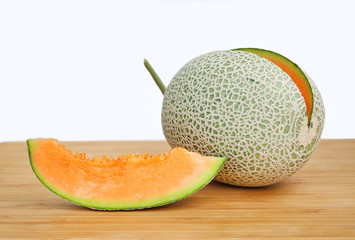 Sliced and cut cantaloupe melon on wood board.