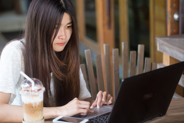 Women use laptop with ice coffee on wood table