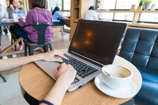 Women hand use laptop with coffee cup on wood table