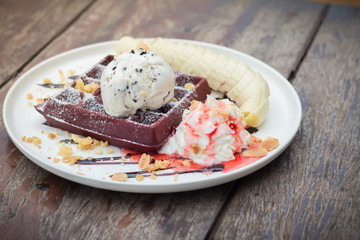 chocolate waffles with vanilla ice cream, banana, whipped cream and strawberry syrup
