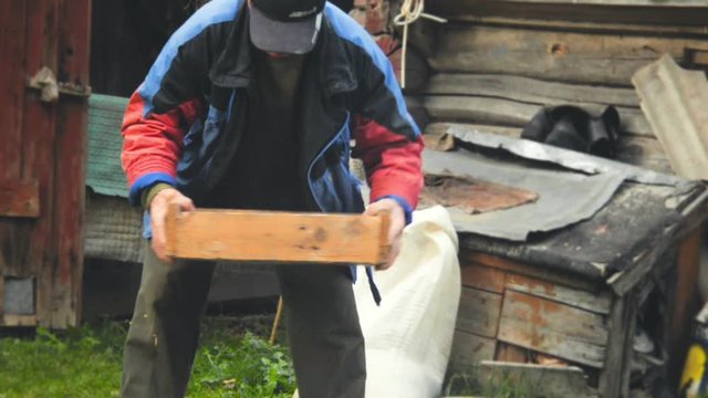 The farmer sifts the grain manually. Hands of the worker who sifts the grain of oats through a sieve. Hands of an elderly person. Disappearing profession concept