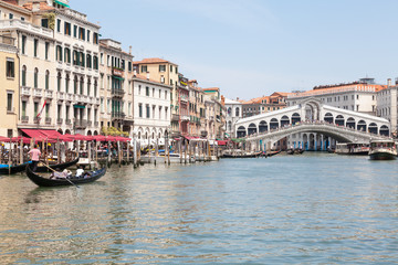 Rialto Bridge, Venice, Veneto,  Italy. Gondolas and vaporettos on the Grand Canal with reflections...