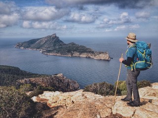 Hiker in the Tramuntana mountains looking at the island of Sa Dragonera, Mallorca, Spain