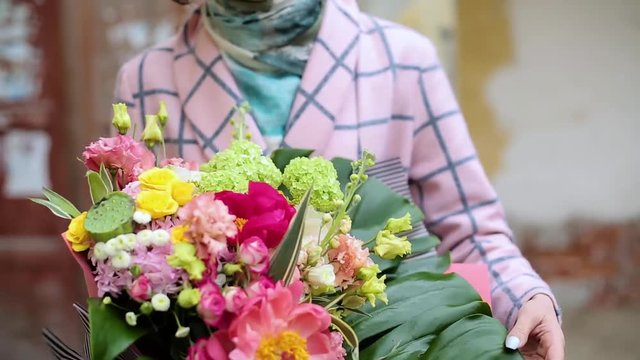 Beautiful young woman in a coat with a bouquet of flowers