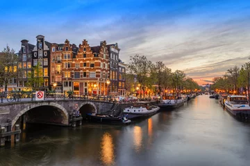 Fotobehang De stadshorizon van Amsterdam aan de waterkant van het kanaal bij zonsondergang, Amsterdam, Nederland © Noppasinw