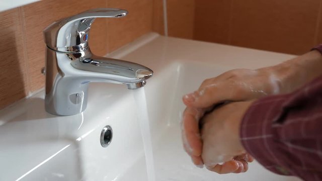 Man washing hands under tap water