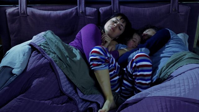 Family hugging in bed sleeping at night