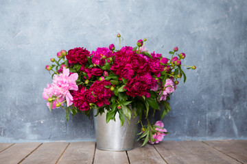 Fresh peonies flowers bouquet on a floor in front of wall
