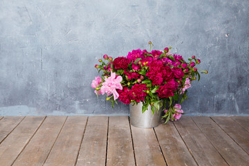 Fresh peonies flowers bouquet on a floor in front of wall
