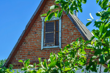 Green old attic on the roof. The roof of the old house against the blue sky