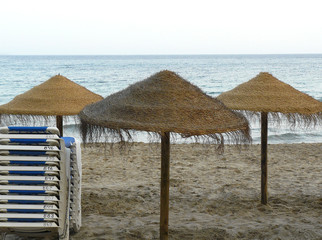 Tres sombrilas de brezo en la playa