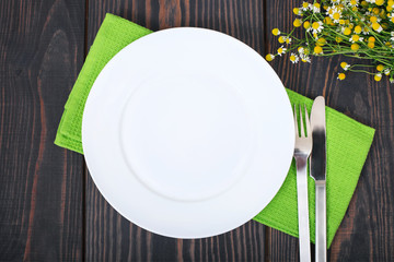 The knife, fork and white plate on a green napkin.