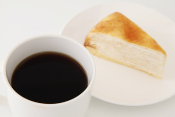 マグカップにいれたホットコーヒーとミルクレープ 白背景