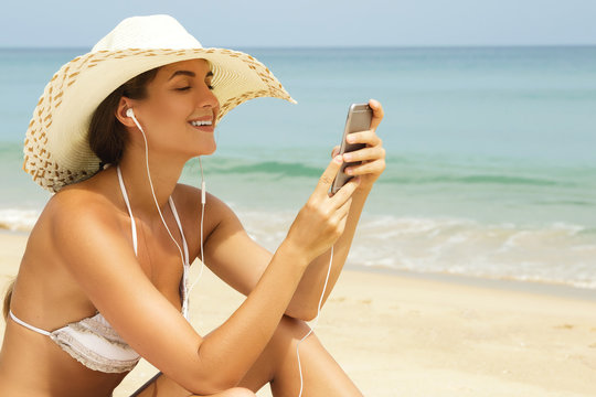 Happy woman is listening music on the beach