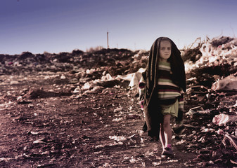 Sad girl on the landfill walking along the road