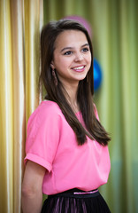 A beautiful girl stands near the curtain and laughs.