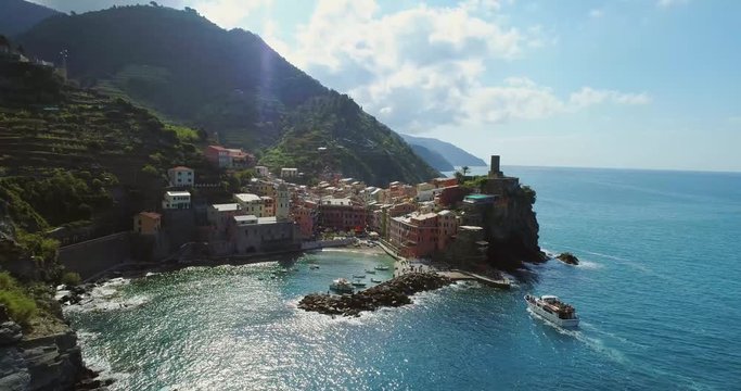 aerial view of travel landmark destination Vernazza,small mediterranean sea town, Cinque terre National Park, Liguria,Italy.Sunny, tourists boat approaching harbor. 4k drone forward video shot