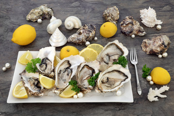 Fresh oysters on crushed ice with lemon fruit, parsley with decorative pearls, shells and an...