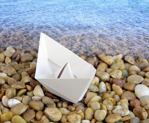 The ship is made of paper by means of technology of origami. The ship is on the beach..