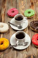 Two cups with coffee and donuts on a wooden background