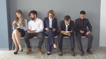 Recruitment to the company. Young applicants are awaiting interview. a group of young people bored waiting for job interview.
