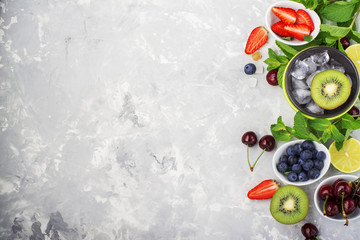 Fototapeta na wymiar Ingredients healthy diet family meals: fresh juicy fruits and berries with mint and ice to prepare a healthy summer desserts, refreshing beverages, to add to cereal, for making smoothies on a light