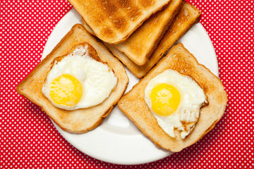 Toasts and eggs on a plate on a red table