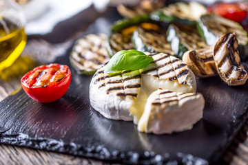 Camembert cheese. Grilled camembert cheese with zucchini tomatoes olive oil and basil leaves. - obrazy, fototapety, plakaty