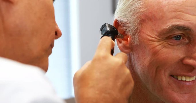Doctor examining patients ear with otoscope