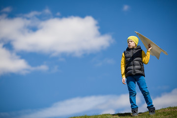 Cute kid boy launching paper airplane in the park. Small child having fun and playing with big handmade plane. Activities with children outdoors. Lifestyle