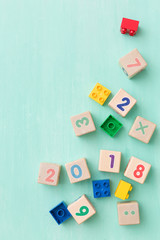 Obraz premium Wooden cubes with numbers and colorful toy bricks on a turquoise wooden background.