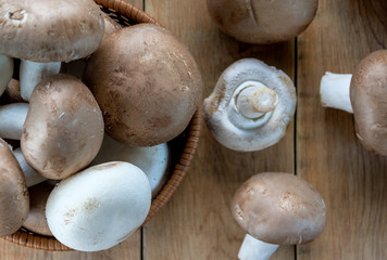 Champignons, mushrooms in the wicker basket and on wooden table