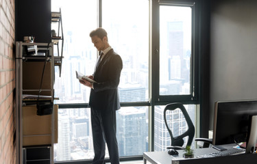 Fototapeta premium Young businessman in suit is enjoying literary work