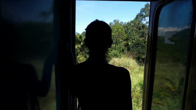 Silhouette of woman looking out of door during train ride, super slow motion 120fps
