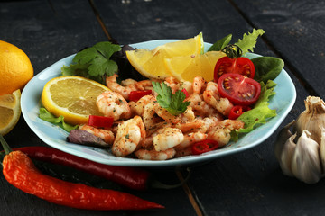 fresh shrimps served on a plate with garlic onion, lemon and chili