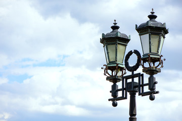 Fototapeta na wymiar Beautiful old vintage lantern on the sky background in the city park