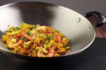 Udon stir-fry rice with shrimp and vegetables in wok pan on black burned stone background