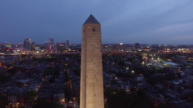 Aerial shot of twilight Bunker Hill Monument in Charlestown with downtown Boston skyline in the background