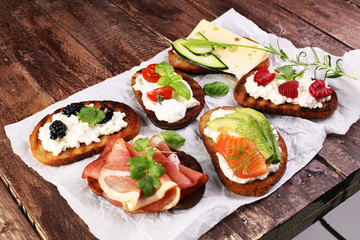 Bread Brushetta or authentic traditional spanish tapas set for lunch table. Sharing antipasti on party or summer picnic time over wooden rustic background.