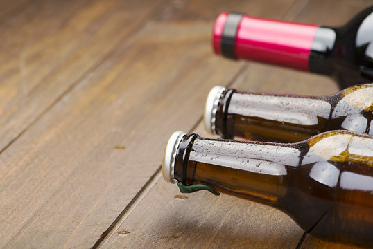 Close-up Of Two Beer Bottles And One Wine On Wooden Table. Copy Space.