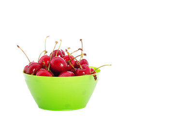 Juicy cherries in a green bowl on a white background