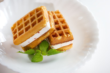 Viennese waffles with souffle,strawberry pieces and mint on a white plate