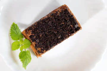 Chocolate cake with chocolate chips and mint on a white plate