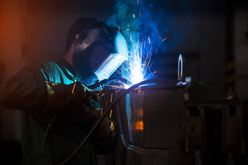Young industrial worker welding in the factory