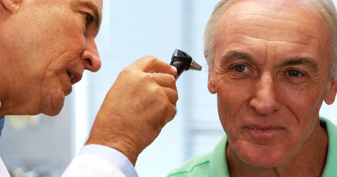 Doctor examining patients ear with otoscope