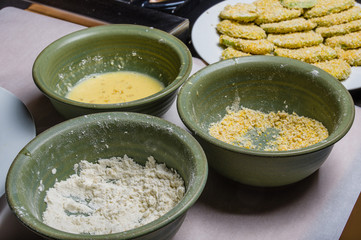 Applying cornmeal dredge to tomato slices