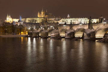 Night romantic snowy Prague gothic Castle and St. Nicholas' Cathedral with Charles Bridge, Czech republic