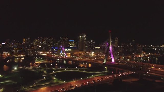 Sliding flying aerial shot of famous landmark Zakim Bridge in Boston at night with traffic on the bridge
