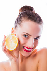 Portrait of young cheerful woman with bare shoulders who keeps one half of lemon in hand near her face on the white background